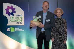 Image of Professor Davey Jones holding the NERC Impact Award trophy with Professor Louise Heathwaite 
